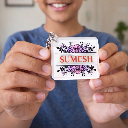 Child holding a name tag with 'Sumesh' on it, showing it to the camera and attaching it to a backpack.